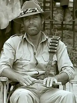 Richard Chamberlain sitting on a film set