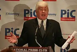 Jack Kemp at a podium with his arms up.