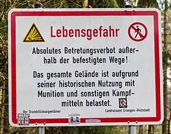 German safety sign warning to stay on paths due to danger from unexploded military bombs
