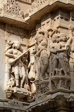 Sculptures on wall. Instrument resembling Rudra veena, far left.