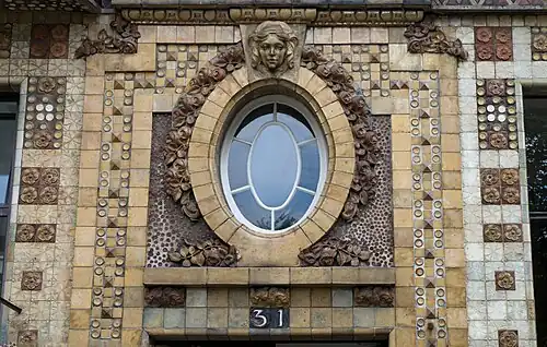 Louis XVI style-inspired medallion-shaped oculus, with rose garlands at the top, of Rue Campagne Première no. 31, Paris, by Alexandre Bigot (ceramist) and André Arfvidson (architect), 1911[18]