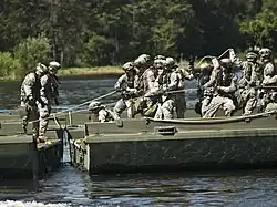 A group of soldiers in green fatigues assembling a bridge