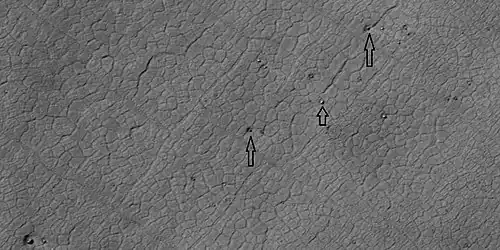 Close view of polygons, as seen by HiRISE under HiWish program. Arrow point to boulders that sit inside of small craters. The pits may have formed from the interaction of winds around the boulders. Winds may go faster near the boulder; hence, causing more erosion.