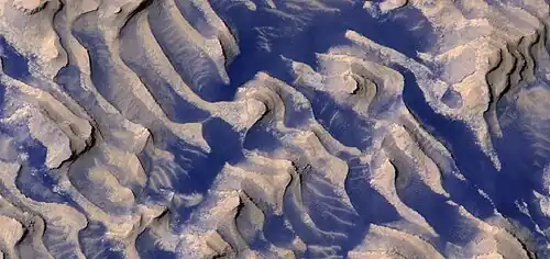 Close, color view of layers and dark dust on floor of Danielson Crater, as seen by HiRISE under HiWish program Boulders are visible in the image.