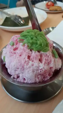 A bowl of Malaysian ais kacang topped with rose syrup and cendol