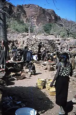 Villagers selling baskets and meat at Tireli market under the Bandiagara Escarpment in the background, Mali 1984