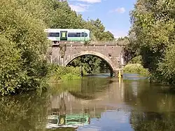 An electric train crossing an arched bridge over a river