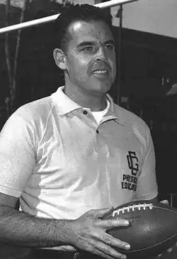 Otto Graham shown from about the waste up smiling and holding a football.