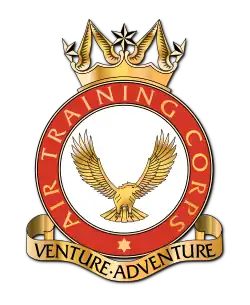 A heraldic badge of the Air Training Corps. Its motto, 'Venture Adventure' is contained in a stylised scroll at the foot of the badge.