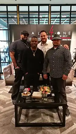 Musical group All-4-One, standing behind a coffee table