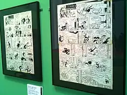 comic book pages displayed in frames on a wall