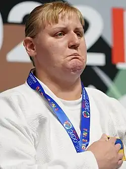 Photograph of Harnyk with a medal around her neck and her right hand on her hearth
