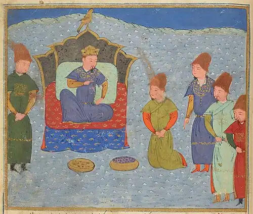 Five men gather around a man sitting cross-legged on a throne.
