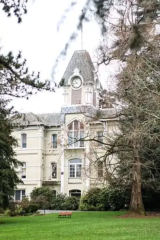 Front view of the building's exterior showing all three floors and the dense landscaping surrounding it
