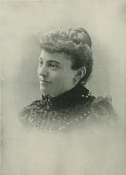 B&W portrait photo of a woman with hair in an up-do, wearing a dark blouse.
