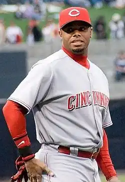 A man in a grey baseball uniform with red sleeves and a red hat with a white "C" on it.