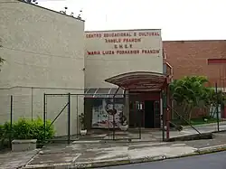 Facade of a two story school surrounded by a chain-link wire