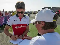 Leclerc signing a fan's autograph book at the 2018 British Grand Prix