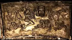 A broken wheel held by a large bearded man and a leaping man on the Gundestrup cauldron (plate C).