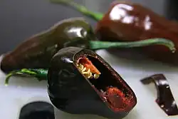 One black chilhuacle chile split in half; other varieties are in the background.