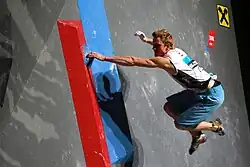 A climber using the dyno technique on an indoor climbing wall