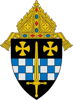 An image of a coat of arms: a golden sword laid over a fess chequy blue and silver and two gold rounded crosses pattée in chief, with a bishop's mitre surmounting the shield.