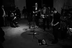 A band dressed in black shirts playing music surrounded by people