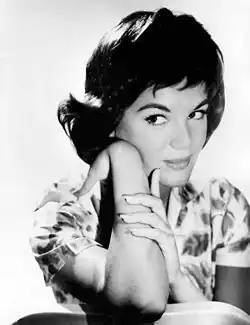 Black-and-white headshot of Connie Francis looking calmly to the side while leaning on her arm. She is a white woman with dark, short hair in bouffant style, wearing a light dress.
