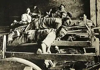 Vieille photographie montrant des émouleurs allongés entrain d'émoudre leurs lames de couteaux.