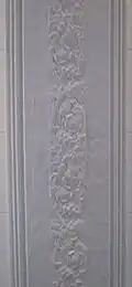A white plaster ceiling beam with a floral pattern in relief
