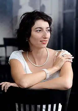 Simona Babčáková sitting backwards on a chair, looking left of camera and smiling