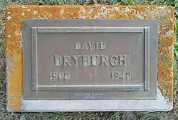 Bronze plaque mounted on a granite base, inscribed with his name, birth year and death year, and a smaller bronze plate attached beneath with his wife's name and dates