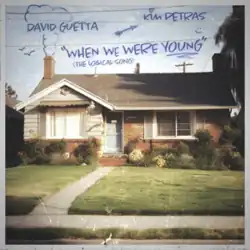 An old image of a house with different drawings in blue ink (including a chimney smoke, birds, an arrow, and a smiley face). The word "Young" in the song's title is underlined while the "i" in Kim Petras's name has a heart on it.