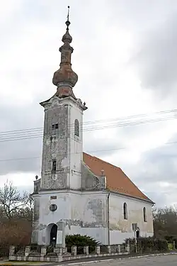 A white, single steepled, Calvanist church is depicted. The church is in poor condition with the paint deteriorating.