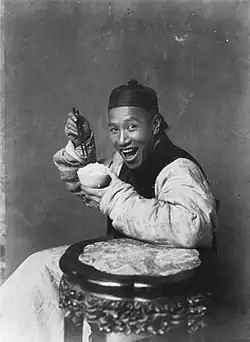In the late 19th century and early 20th century, photographs taken in the United Kingdom rarely depicted people smiling, in accordance with the cultural conventions of Victorian and Edwardian society. In contrast, the photograph Eating Rice, China depicts a smiling Chinese man.