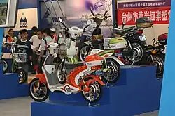 Various electric bicycles on stands at a busy trade show