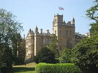 A mansion surrounded by trees and hedges.