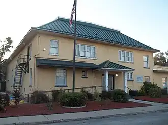 A two-story tan building with green roof
