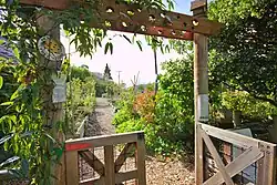 A wooden gate leading to a busy garden