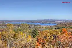 Flat landscape with lake in background and fall-colored orange and yellow trees