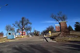 The entrance to Flandreau Indian School - a road with a booth on the left and multiple signs with the name of the school.