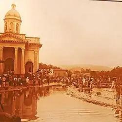 People navigating around a flooded street in San Salvador in front of a church