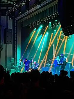 Portrait photo of Foxing (band), performing live in concert, at Roxian Theatre, in Pittsburgh, Pennsylvania. Photo shows members of the band on stage with audience in foreground.