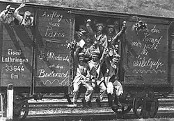 Men waving from the door and window of a rail goods van