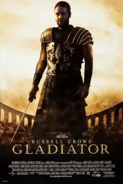 A man standing at the center of the image is wearing armor and is holding a sword in his right hand. In the background is the top of the Colosseum with a barely visible crowd standing in it. The poster includes the film's title and credits.