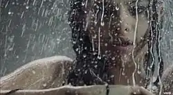 A portrait of a young brunette woman taking a shower.