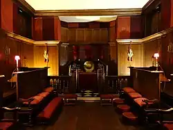 A photograph of the small family chapel, with wooden panelling and red wall hangings