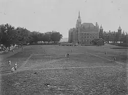 Black and white photograph of a baseball field with Healy Hall in the background
