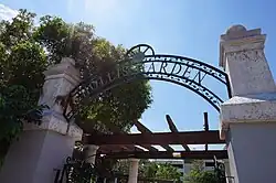 An arched black iron entry sign that says Hollis Garden