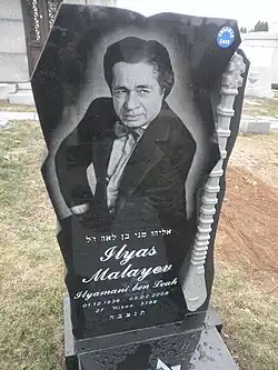 Grave of Mallayev with an homage to his beloved instrument, the tambur, carved into the stone at Mount Carmel Cemetery in Queens, NY, USA